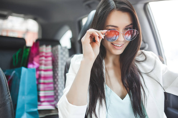 Attraktive junge Frau im Auto mit Einkaufstüten. - Foto, Bild