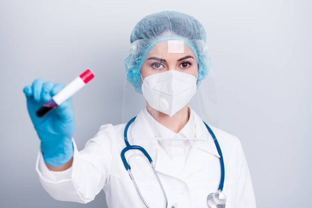 Closeup photo of infection viral doctor experienced nurse hold blood probe covid patient positive result wear coat mask facial plastic protection shield surgical cap isolated grey background - Fotografie, Obrázek