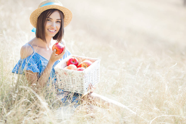 Χαριτωμένη νεαρή γυναίκα με μήλα έξω. Θερινό φόντο. - Φωτογραφία, εικόνα