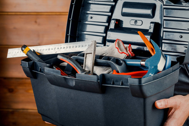 Bau und Reparatur - ein männlicher Arbeiter oder Bauarbeiter mit Arbeitswerkzeug in einer Schachtel. - Foto, Bild