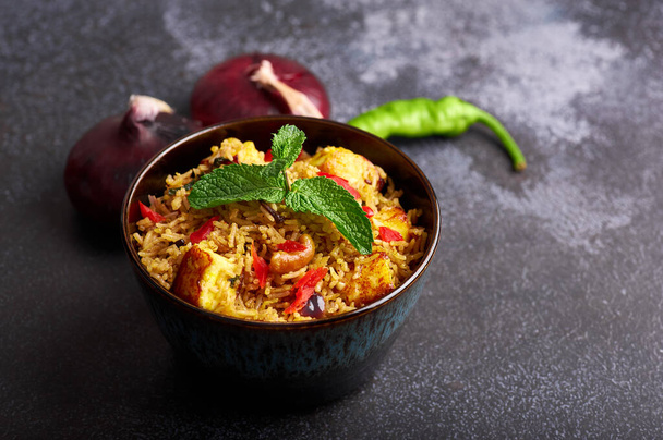 χορτοφάγος paneer biryani σε μαύρο φόντο. paneer biryani είναι παραδοσιακό veg ινδική κουζίνα πιάτο με τυρί πανίρ, ρύζι μπασμάτι, μασάλα, πιπέρι τσίλι, μέντα και πολλά άλλα μπαχαρικά. Αντιγραφή χώρου - Φωτογραφία, εικόνα