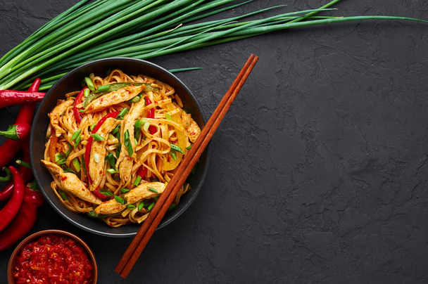 Chicken Schezwan Noodles or Hakka or Chow Mein in black bowl at dark background. Schezwan Noodles is indo-chinese cuisine hot dish with udon noodles, vegetables and chilli sauce. Copy space - Photo, Image