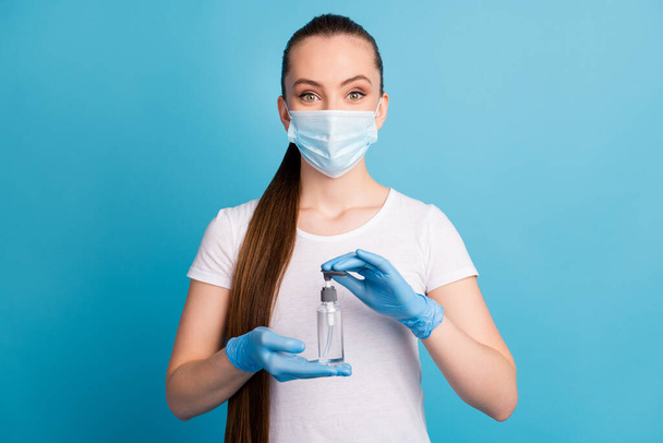 Photo of pretty cheerful lady hold hands antiseptic big bottle disinfection safety concept advising sterile hundred protection wear gloves face mask isolated blue color background - Fotó, kép