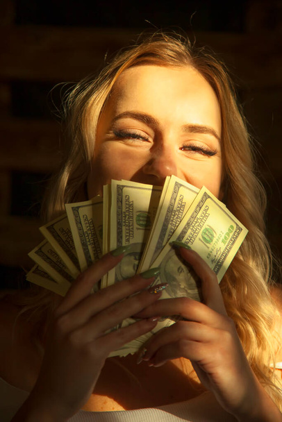 A pénz a legjobb motiváció. Portré nagyon boldog fiatal gyönyörű nő kezében amerikai dollár számlák szimbóluma a gazdagság és a siker. - Fotó, kép