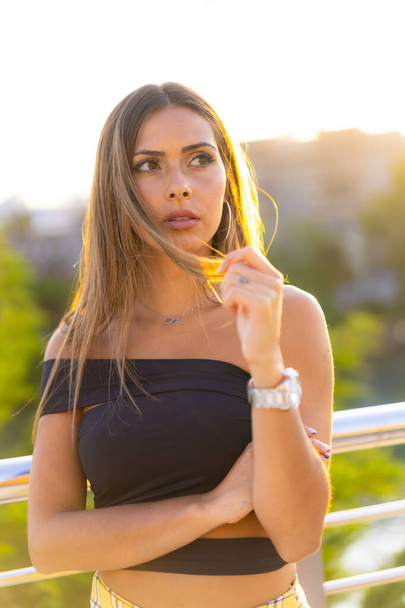 Lifestyle session, a young brunette in a black bonded top and a yellow skirt on a sunset in the city - Foto, Imagen