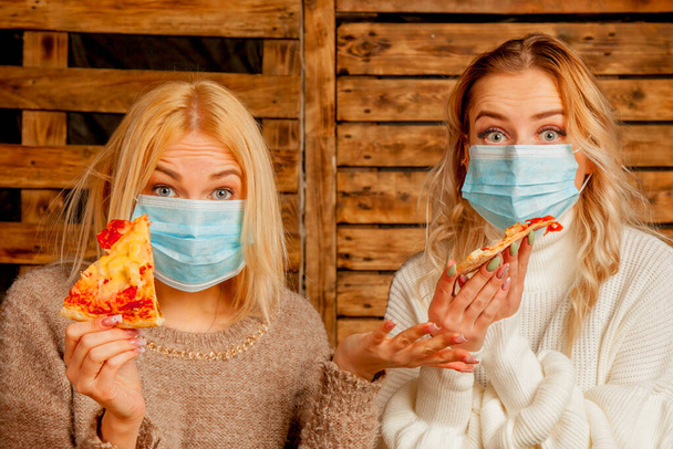Coronavirus, ατμοσφαιρική ρύπανση pm2.5, και καραντίνα έννοια. Οι στρεσαρισμένες όμορφες γυναίκες δεν μπορούν να φάνε πίτσα στο εστιατόριο επειδή φορούν μάσκα αναπνοής..  - Φωτογραφία, εικόνα