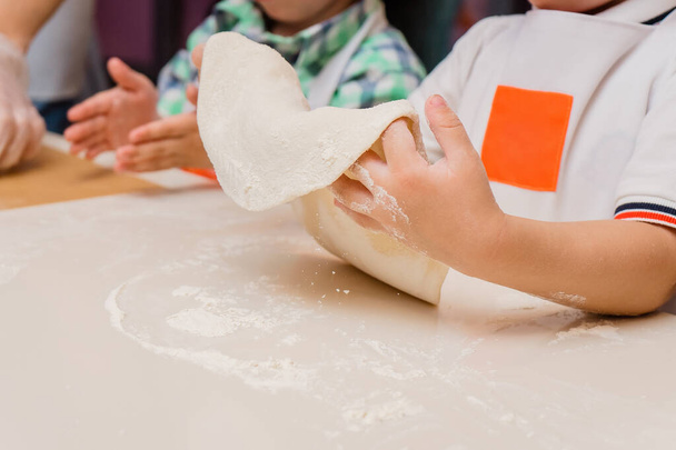 The child cooks. Hands hold the base for pizza dough. Kids' cooking class on baking - Photo, Image