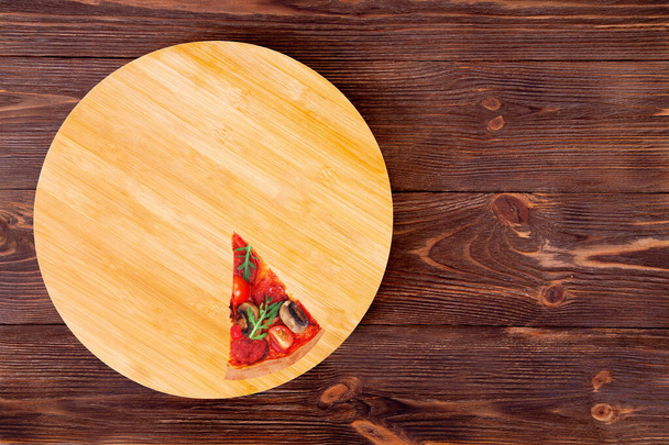Una rebanada de sabrosa pizza con salami picante, rúcula, tomates cherry, champiñones y texas mezcla de especias, en un plato de madera que está en la mesa rústica de madera, vista superior y espacio de copia
 - Foto, imagen