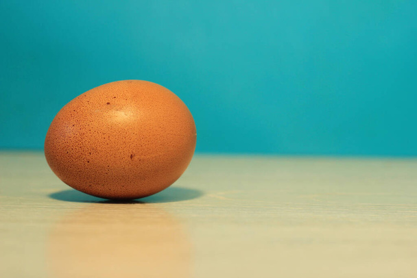 um ovo de galinha na mesa em um fundo azul
 - Foto, Imagem