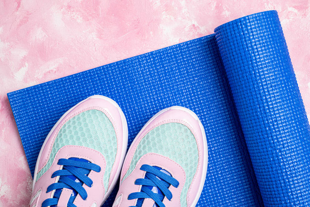 Спорт и здоровый образ жизни. Йога-коврик и спортивная обувь на розовом фоне. Спортивное оборудование. Модная женская спортивная одежда для фитнеса и йоги. Копирование пространства
 - Фото, изображение