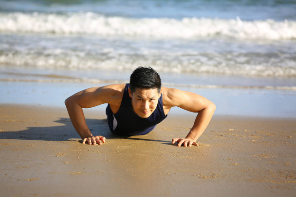 若い男がビーチで運動をしていて - 写真・画像