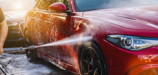 Nettoyage de voiture rouge en utilisant de l'eau à haute pression dans un lavage de voiture
 - Photo, image