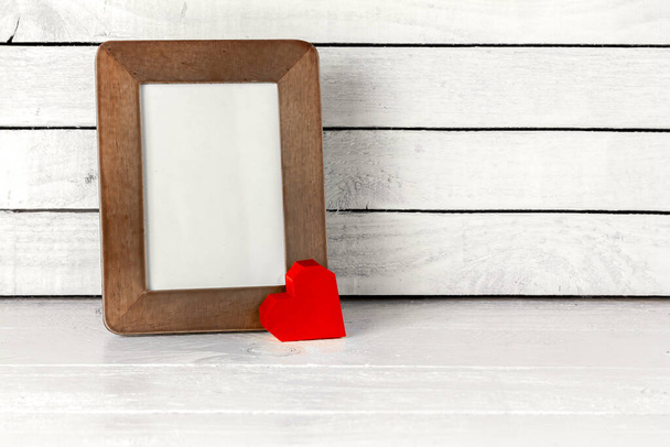 Photo Frame with Red Heart Paper on table over white wood background - Photo, Image