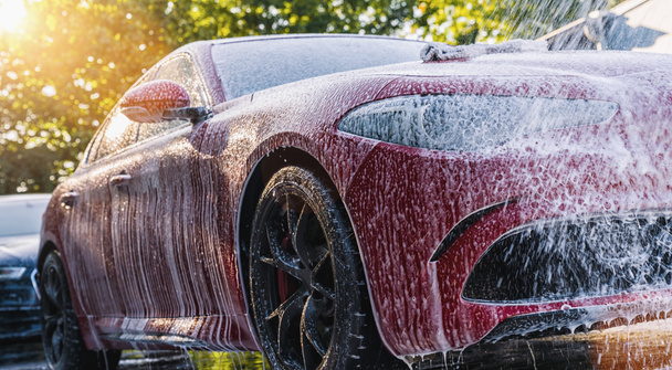 Pulvérisation de mousse sur une voiture rouge avec mousse haute pression pistolet lavage de voiture au service de lavage de voiture
 - Photo, image