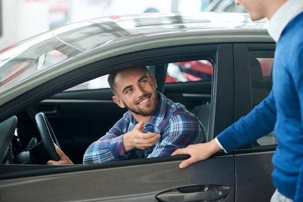 Car seller and customer handshake in car dealership. - Фото, изображение