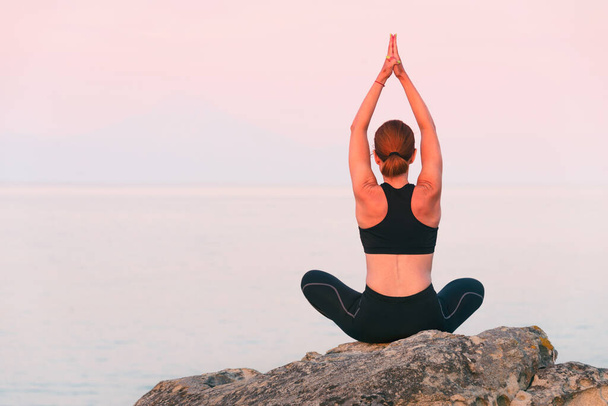 Európai nő, aki fitnesz jóga edzést gyakorol a parton naplementekor. Képzés a tengeri és hegyi háttér. Az egészséges életmód és az egyéni szabadtéri sportok koncepciója társadalmi távolságtartás mellett. - Fotó, kép
