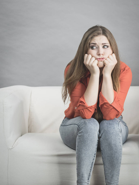 Sad worried woman waiting of something sitting on sofa being very nervous and stressed. - Foto, Imagen