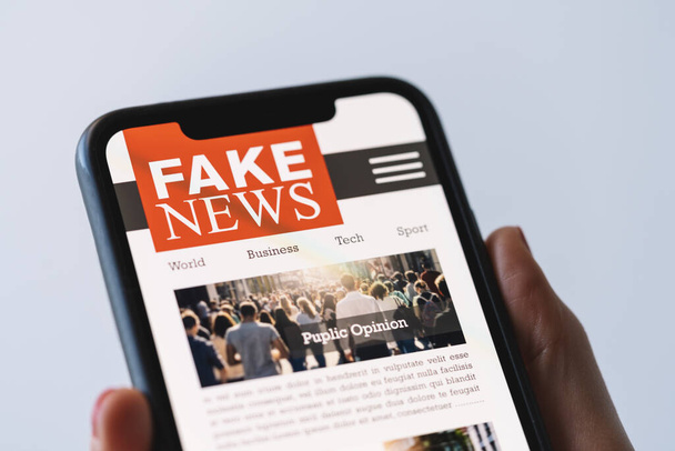 Online fake news on a mobile phone. Close up of woman reading Fake news HOAX or articles in a smartphone screen application. Hand holding smart device. Mockup website. Fake Newspaper portal. - Φωτογραφία, εικόνα