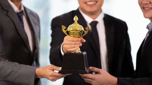 střední část tří podnikatel drží pohár s trofejemi na úspěšné. - Fotografie, Obrázek