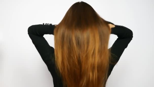 A young beautiful woman straightens her long luxurious hair - Felvétel, videó