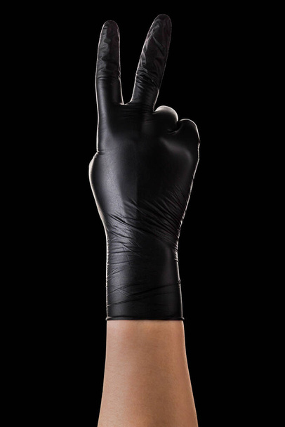 Hand in black gloves showing two fingers up in peace or victory symbol on black - Fotó, kép