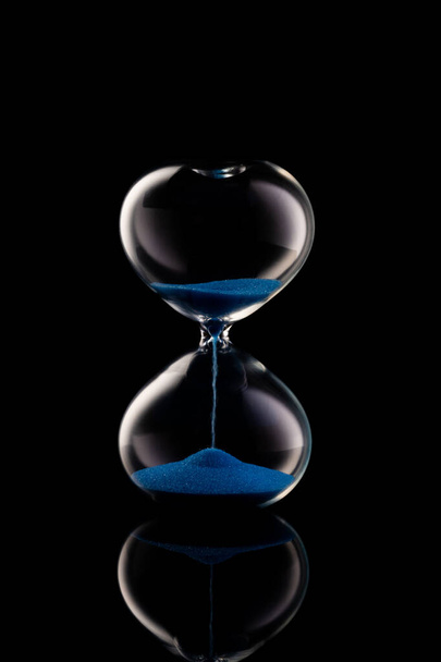 Reloj de arena azul sobre fondo negro
  - Foto, Imagen