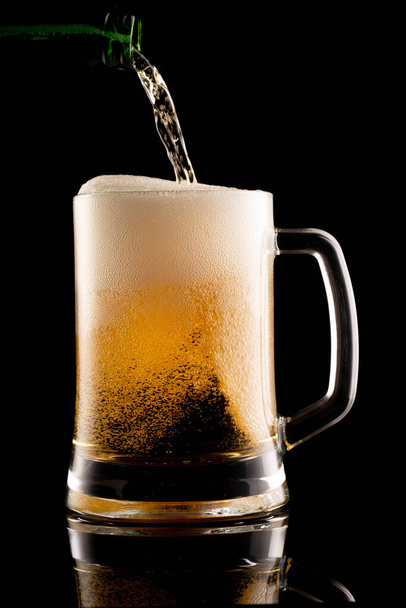 Glas bier met schuim op zwarte ondergrond - Foto, afbeelding