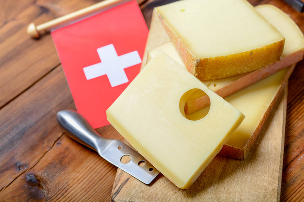 Erilaisia Sveitsin juustoja Emmental tai Emmentaler keskikovaa juustoa pyöreät reiät, Gruyere, appenzeller ja raclette käytetään perinteisen juuston fondue ja gratin ja Sveitsin lippu - Valokuva, kuva