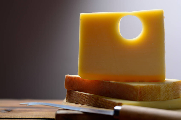 Block of Swiss Emmental or Emmentaler medium-hard cheese with round holes made from cow milk in Canton Bern. - Fotó, kép