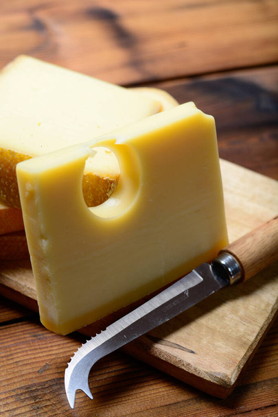 スイスチーズの盛り合わせ伝統的なチーズフォンデュやグラタンに使用される丸い穴、グリュイエール、アペンセラー、ラクレットを持つメンタルまたはエメンタール中ハードチーズ - 写真・画像