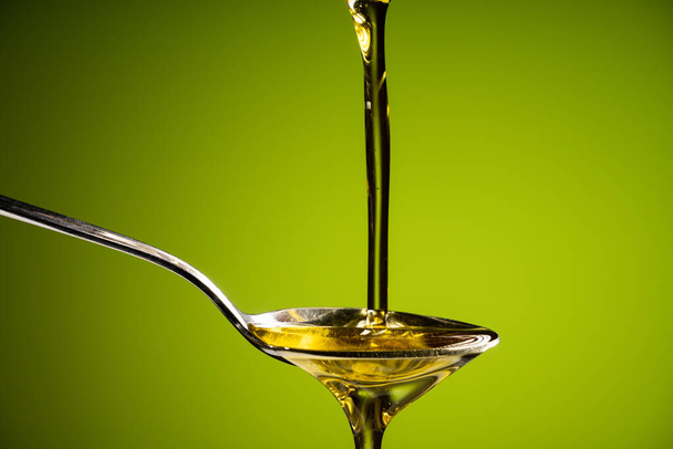 olive oil flowing to the spoon - 写真・画像