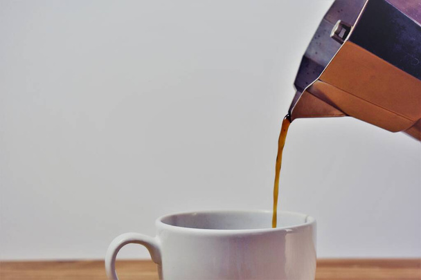 caffettiera che serve caffè in una tazza bianca
 - Foto, immagini