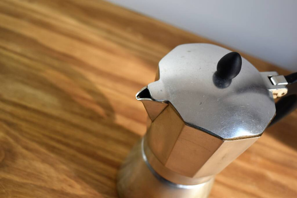 металлическая кофеварка на деревянном столе
 - Фото, изображение