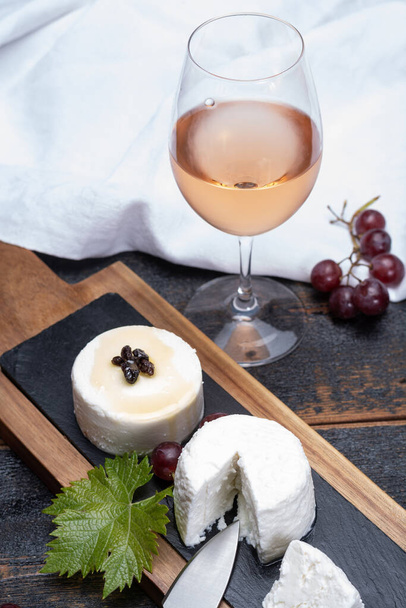 French soft cheeses, variety of different taste goat milk natural cheeses on granite plate close up sesrved as dessert with cold rose wine from Provence - Photo, Image