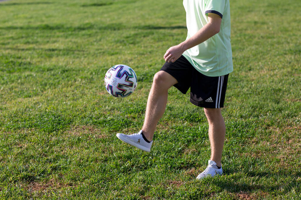 A young boy holding a football ball on a field - Фото, изображение