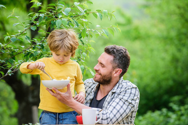 Best weekend ever. healthy food and dieting. Dairy products. family dinner time. Morning breakfast. Vegetarian diet. happy fathers day. Little boy with dad eat cereal. father and son eating outdoor - 写真・画像