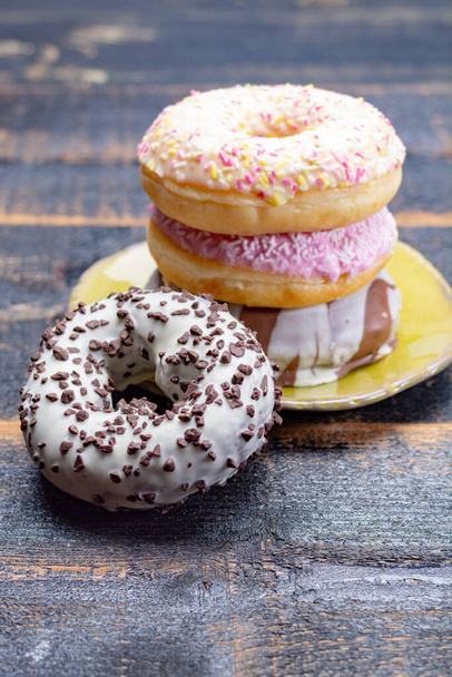 Donuts coloridos de vidro doce de padaria em fundo de madeira preta de perto
 - Foto, Imagem