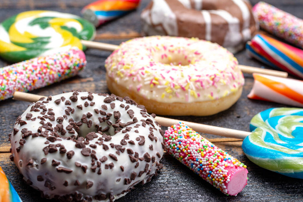Kinderparty Hintergrund mit süßen bunten Donuts und Süßigkeiten in Nahaufnahme auf Holztisch - Foto, Bild