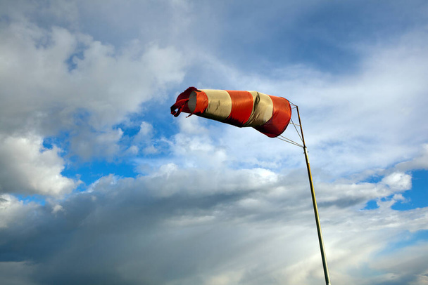 Meteorologie windzak voor de scheepvaart. Rood-witte windsok blaast tegen een blauwe lucht - Foto, afbeelding