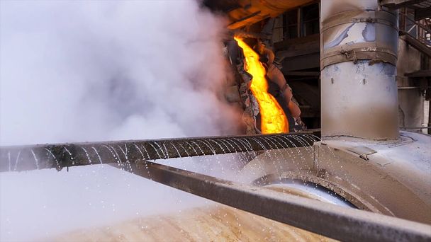 Red hot melted metal flowing inside the chute. Stock footage. Industrial background at the factory hot shop with flowing hot steel near rotating mill being cooled by water. - Photo, Image