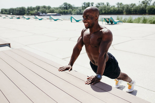 Professional pilates trainer afro-american doing stretching exercises of the spine and back muscles arching in the back - Fotó, kép