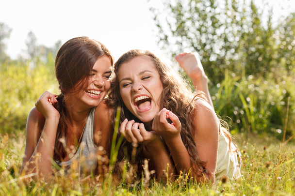 two girlfriends lying down on grass - Photo, Image