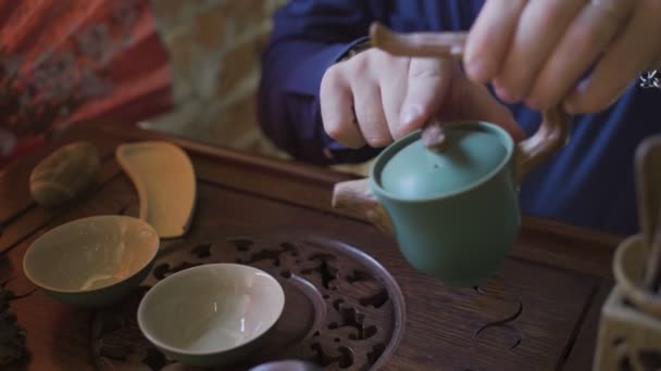 Человек разливает зеленый чай из чайника в Гайван на традиционной китайской чайной церемонии
. - Кадры, видео
