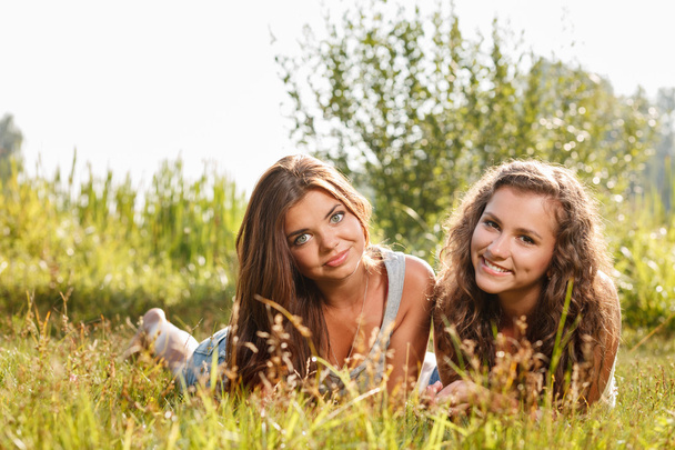 twee vriendinnen liggen op gras - Foto, afbeelding