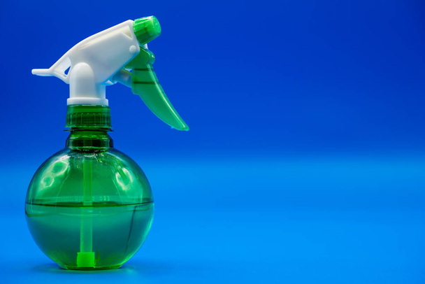 Plastic spray bottle with copy space. Liquid sprayer isolated in a colorful blue background. - Фото, изображение