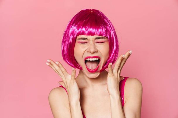 Image of displeased nice woman in wig screaming on camera with eyes closed isolated over pink background - Φωτογραφία, εικόνα