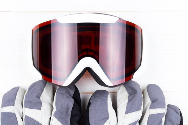 Guantes y gafas de invierno sobre fondo de mesa de madera natural blanca. Concepto de esquí o snowboard. Vista superior plana
. - Foto, Imagen