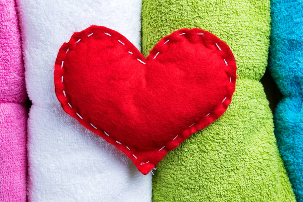 Czerwone domowe serce na kolorowe ręczniki w Walentynki. Romantyczne spa abstrakcyjna koncepcja. - Zdjęcie, obraz