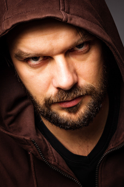 Close-up portrait of threatening man with beard wearing a hood - Photo, image