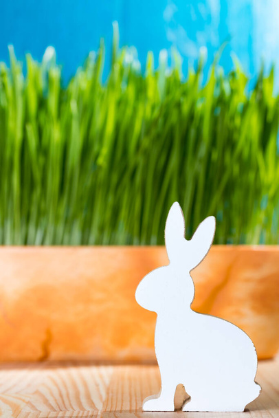 Paskalya tavşanı ahşap heykelcik çimenlerde oturuyor. Bahar zamanı konsepti. - Fotoğraf, Görsel